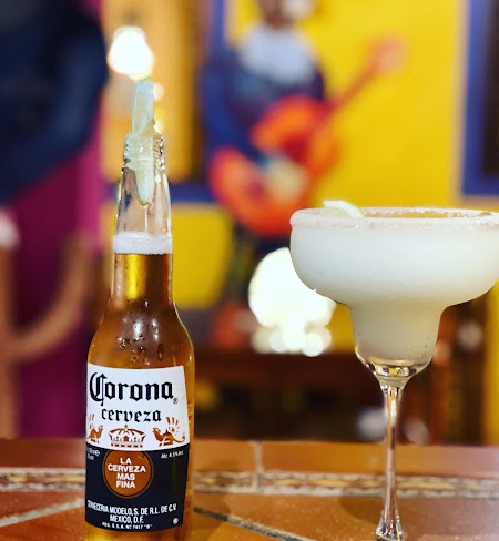 Corona bien fría junto a una margarita